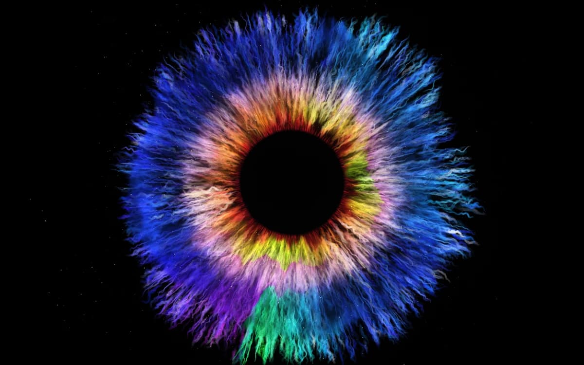 Painted iris on black — coral inner ring dissolving into cobalt blue strokes with cyan and violet accents